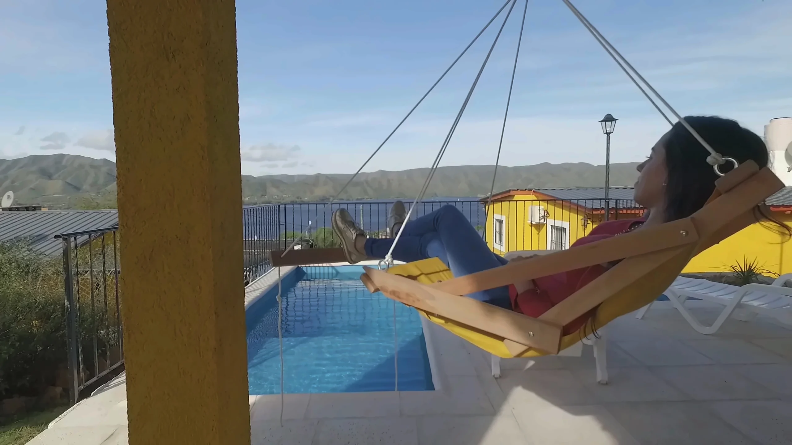 Huésped en una hamaca junto a la pileta, con el lago de fondo